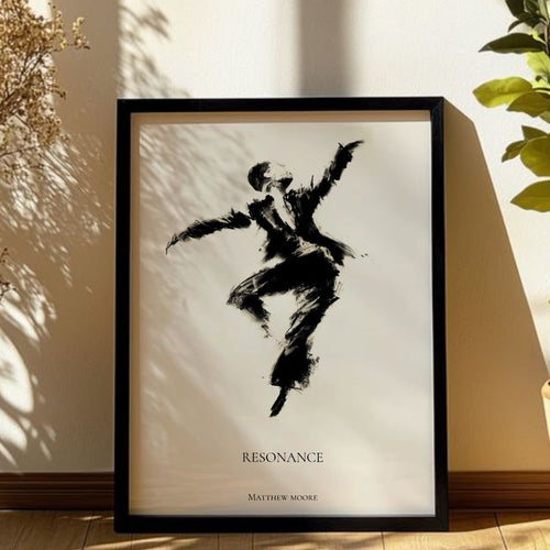 A framed black and white art print featuring a dancer silhouette with the title 'RESONANCE' and 'BAY FLOW WORKS' below, leaning against a wall in a sunlit room with a potted plant and dried branches nearby.